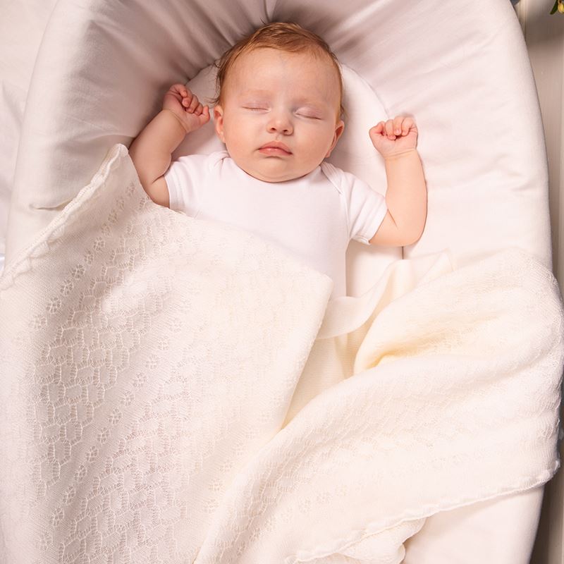 baby in crib with white leaves and flowers 