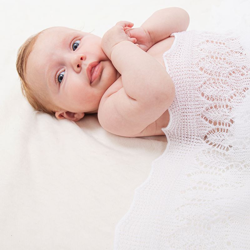 baby laying on white soft lacy cotton shawl